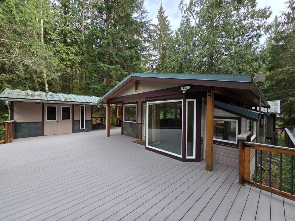 Wooden cabin with large deck in forest.
