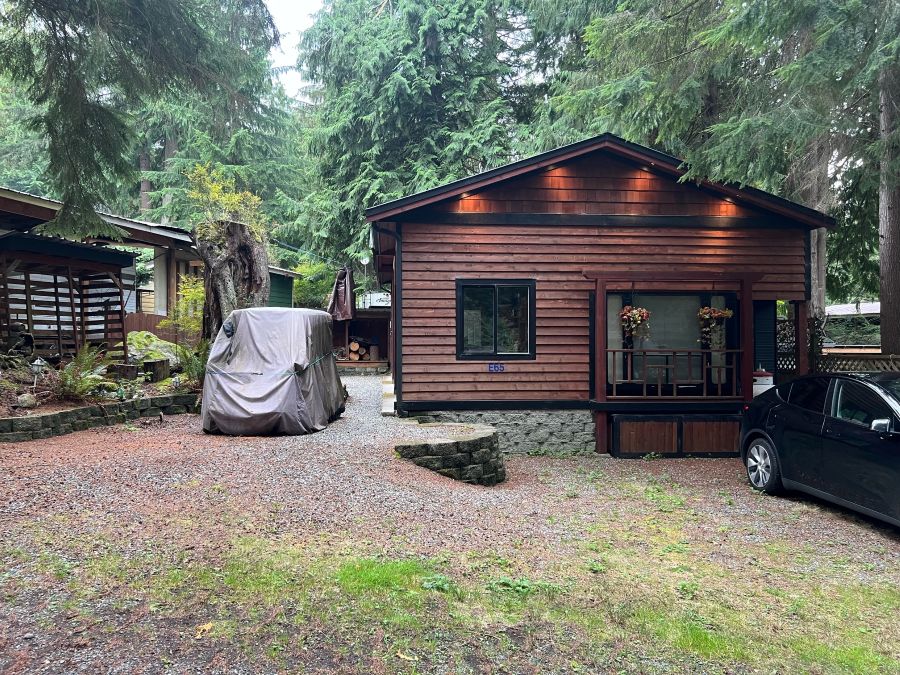 Wooden cabin surrounded by trees and vehicles.