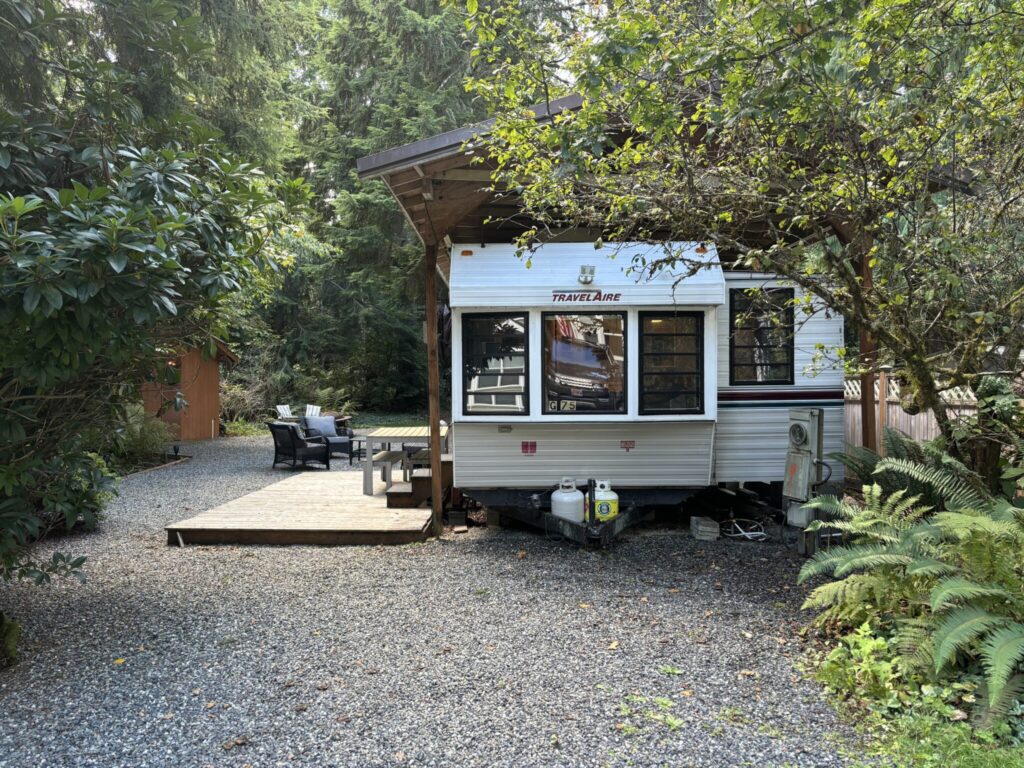 Camper trailer parked in a forest setting.