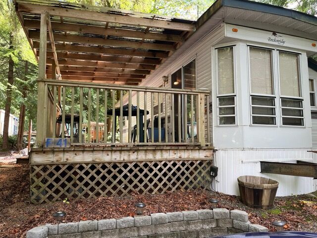 Mobile home with wooden porch and awning.