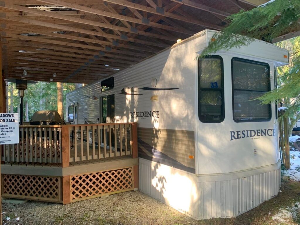 Mobile home with wooden deck and roof.