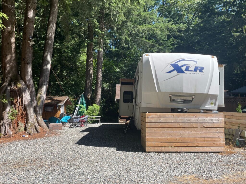 RV parked in wooded campsite area.