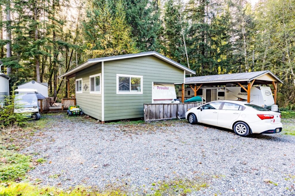 Small house with parked cars and trees.